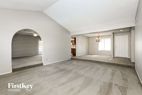 A spacious room with a carpeted floor and a chandelier hanging from the ceiling.