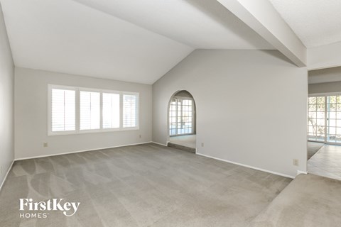 A spacious room with a large window and a doorway leading to another room.