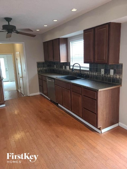 an empty kitchen with a sink and wooden floors