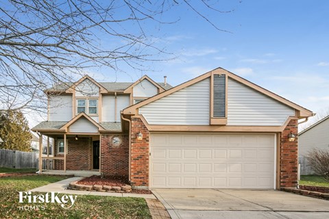 A house with a garage and a brick pillar in front of it.