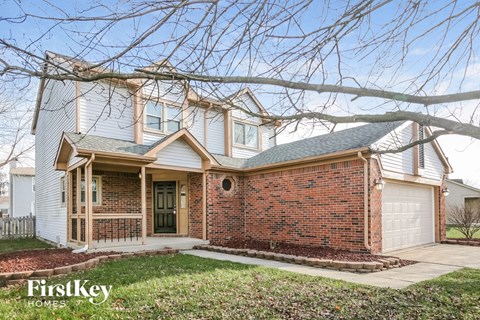 A house with a brick facade and a white garage door is for sale.