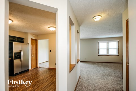 A kitchen with a refrigerator and a living room with a window.