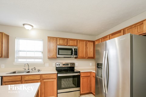 A kitchen with wooden cabinets and a stainless steel refrigerator.