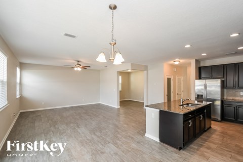 an open kitchen and living room with a kitchen island and a stainless steel refrigerator