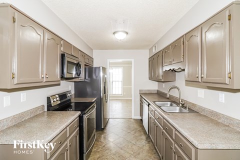 A kitchen with brown cabinets and a black refrigerator.