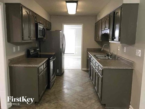 A kitchen with a refrigerator, microwave, and oven.