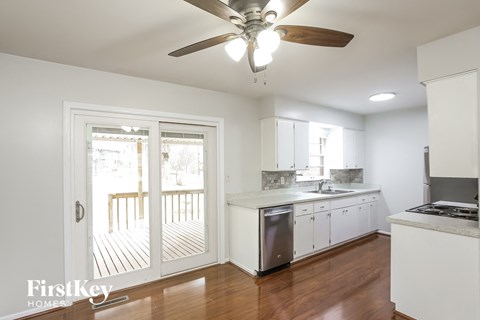 a kitchen with white cabinets and a sliding glass door to a deck