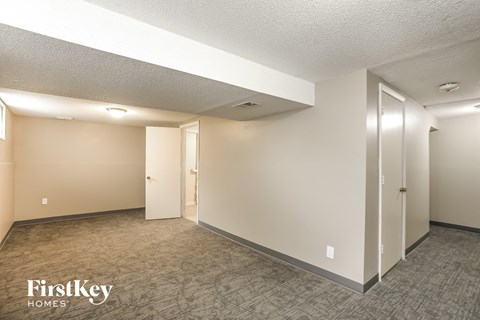 the living room of an apartment with white walls and carpet