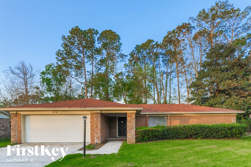 A house with a garage is surrounded by trees.