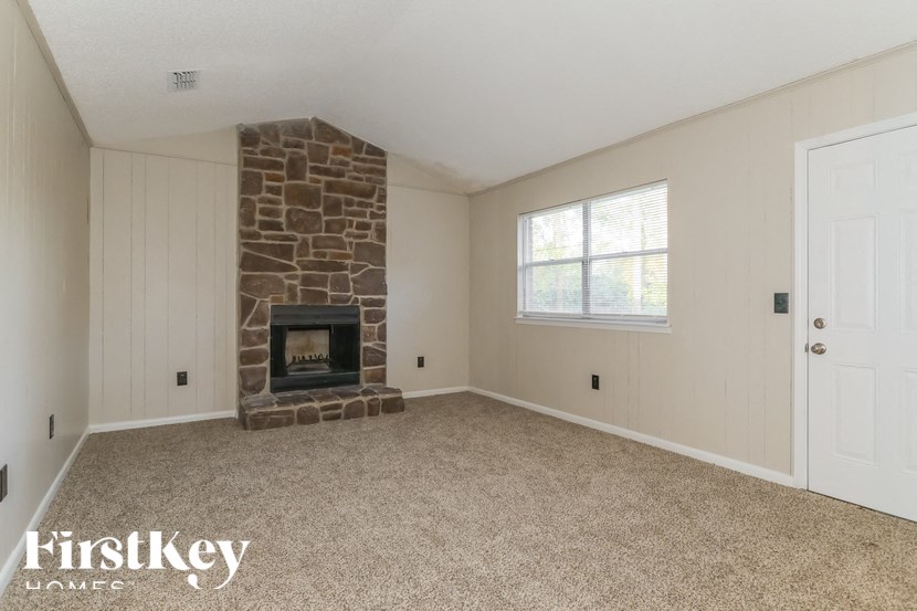 A room with a stone fireplace and a carpeted floor.