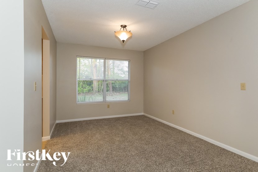 A room with a carpet floor and a window showing a garden outside.