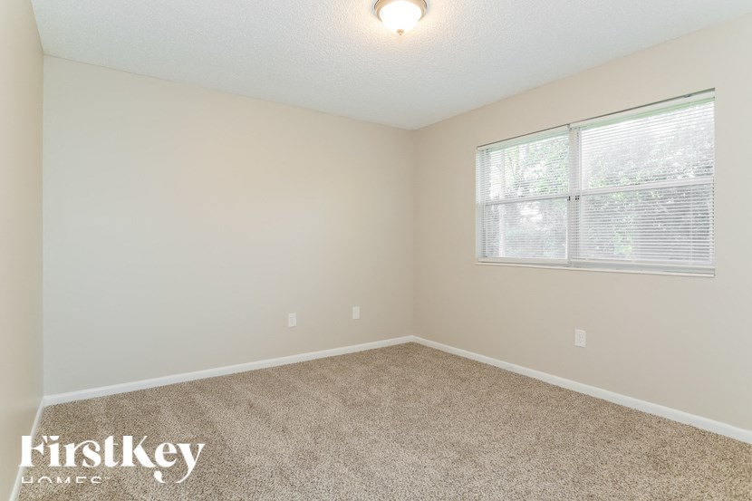 A room with a carpeted floor and a window with blinds.