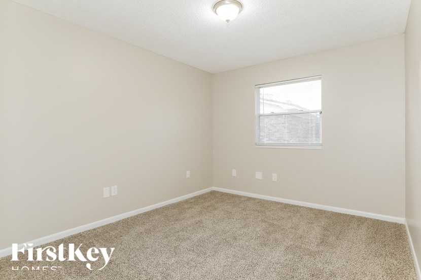 A room with a carpeted floor and a window with blinds.