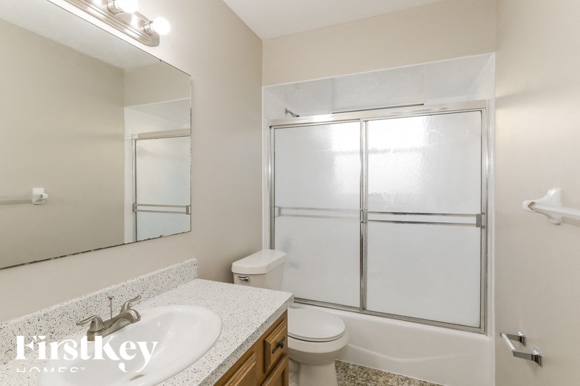 A bathroom with a white sink, toilet, and a glass shower door.