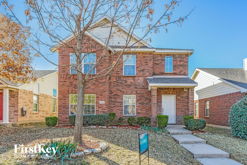 A brick house with a tree in front and a sign that says "FirstKey Homes".