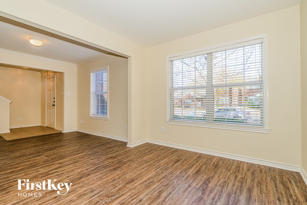 A room with wooden floors and a window with blinds.