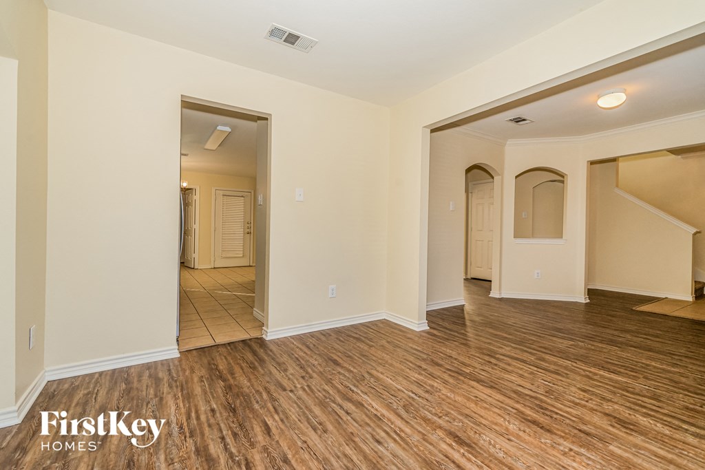 A spacious room with wooden flooring and a doorway leading to another room.