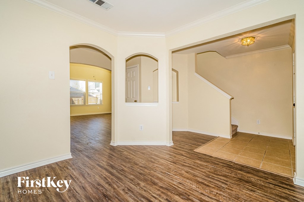 A room with wooden floors and a staircase leading to another room.