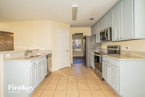 A kitchen with white cabinets and a tiled floor.