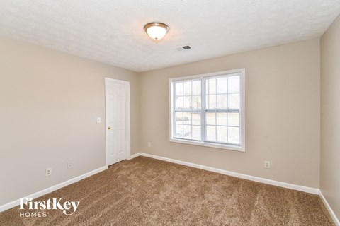 a bedroom with carpet and a window and a door