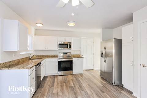 A kitchen with white cabinets and a wooden floor.