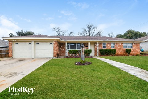 A brick house with a white garage door and a green lawn.