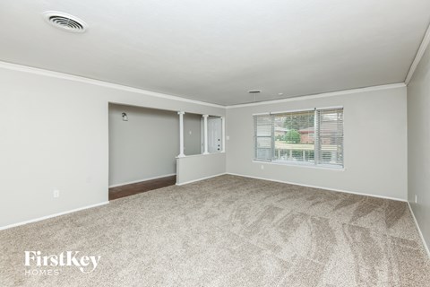 A room with a carpeted floor and a window with blinds.