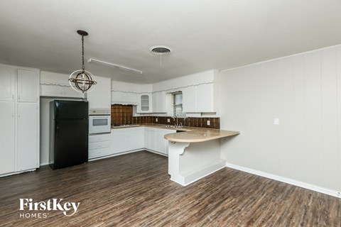 A kitchen with white cabinets and a wooden floor.