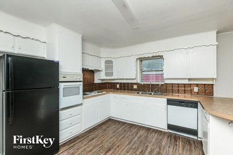 A kitchen with white cabinets and a black fridge.