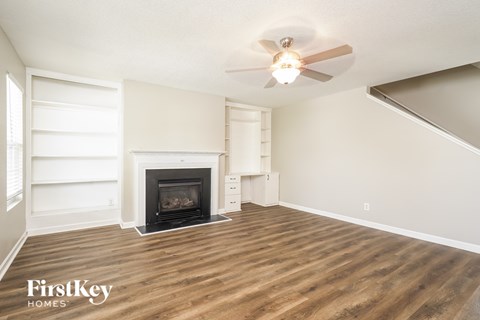 A living room with a fireplace and a ceiling fan.