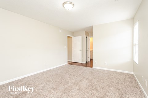 A spacious room with a carpeted floor and a doorway leading to another room.