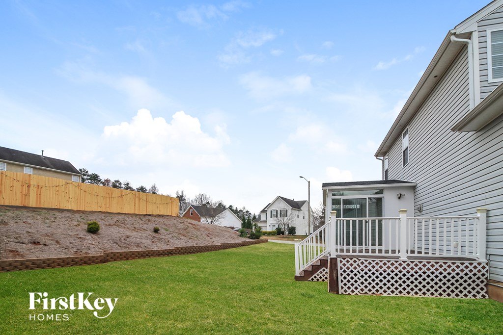 a backyard with a deck and a yard and a house with a fence