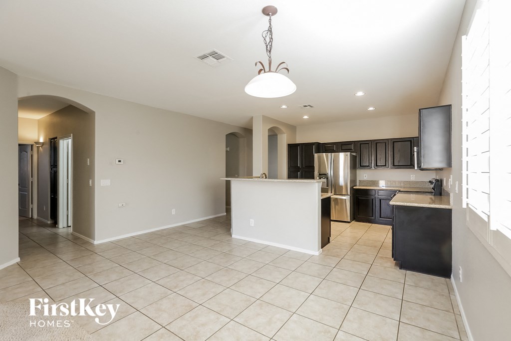 A spacious kitchen and living room with a chandelier and a television.