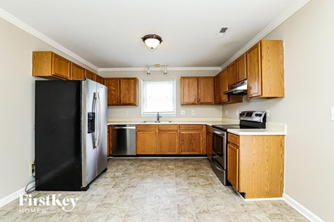 A kitchen with wooden cabinets and a black fridge.