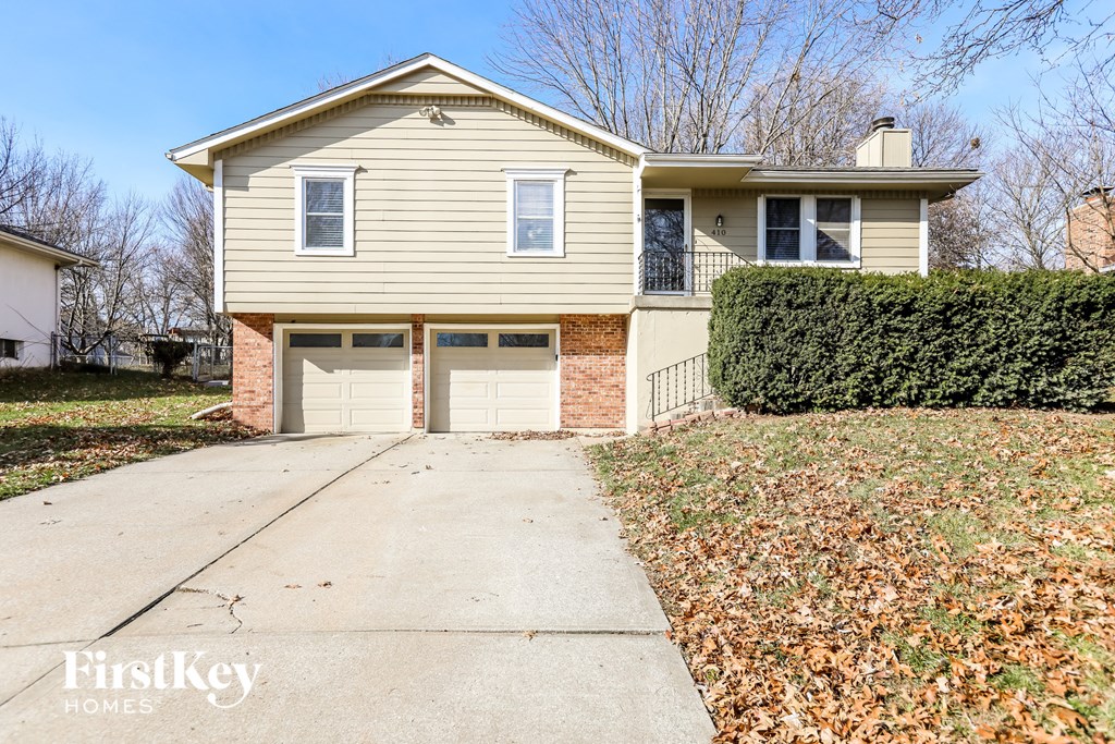 a tan house with two garage doors and a sidewalk