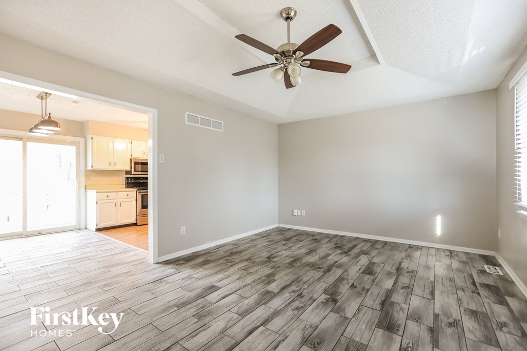 the living room and dining room with wood floors and a ceiling fan