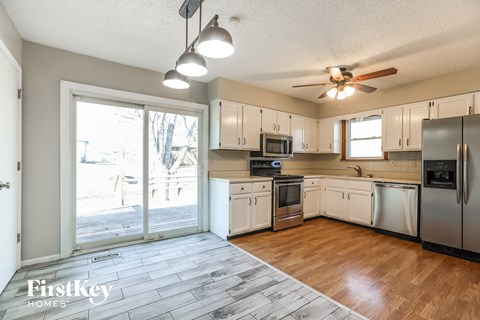 a kitchen with white cabinets and stainless steel appliances and a sliding glass door