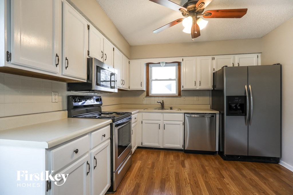 a kitchen with white cabinets and stainless steel appliances and a ceiling fan
