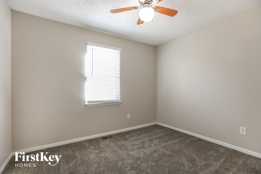 an empty room with a ceiling fan and a window