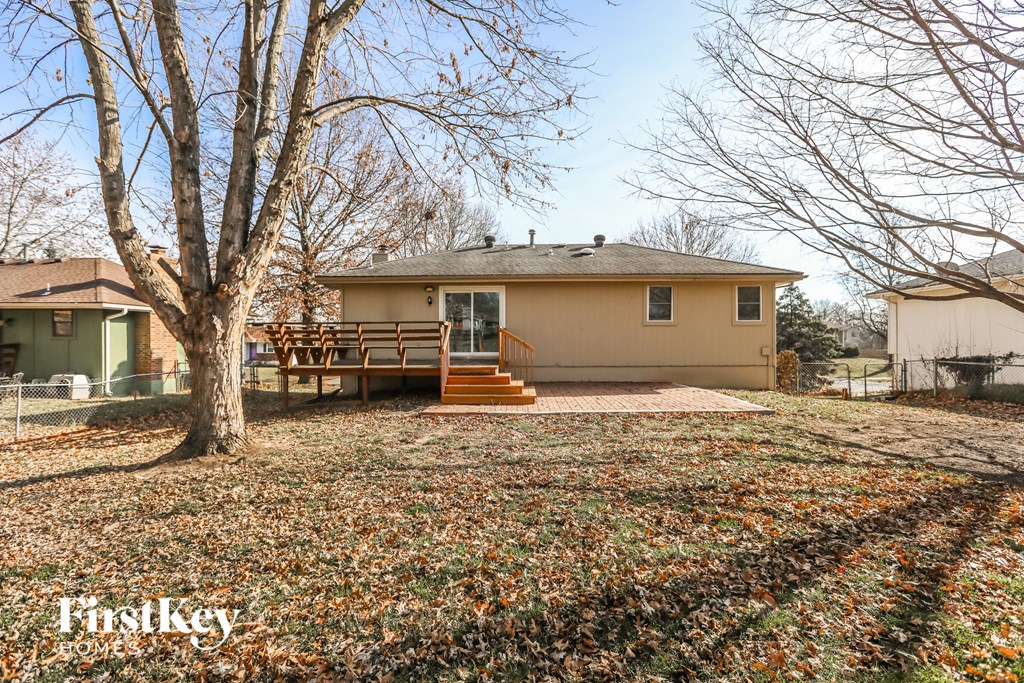 a small yellow house with a deck and a tree