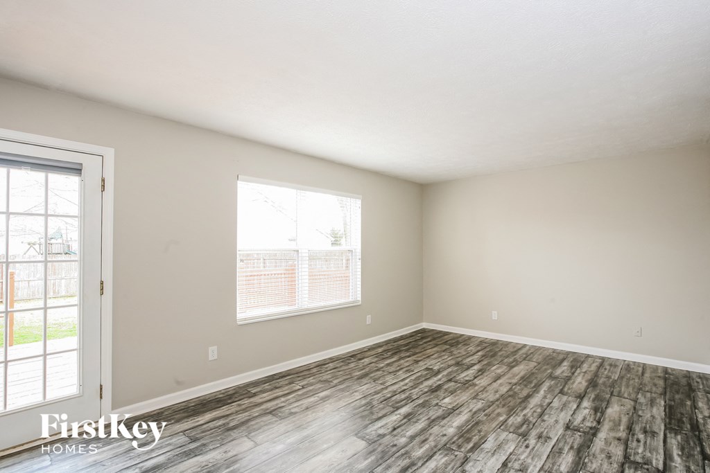 the spacious living room with wood flooring and a window
