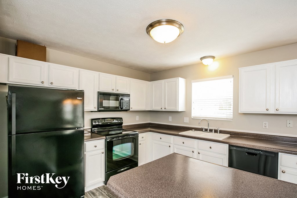 a kitchen with black appliances and white cabinets