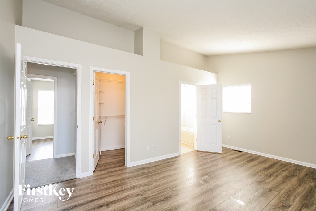 a living room with a hard wood floor and a door to a bathroom