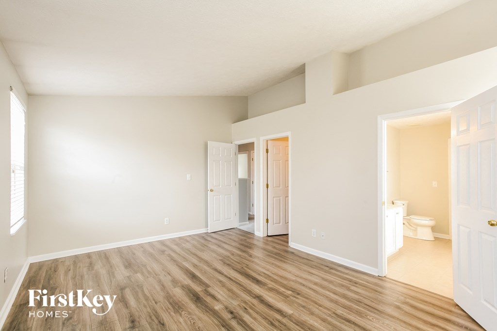 a spacious living room with white walls and wood flooring