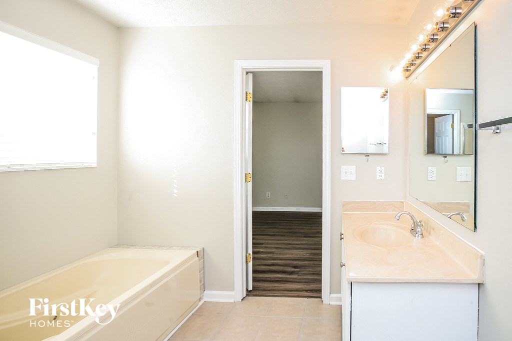 a bathroom with a tub and a sink and a mirror