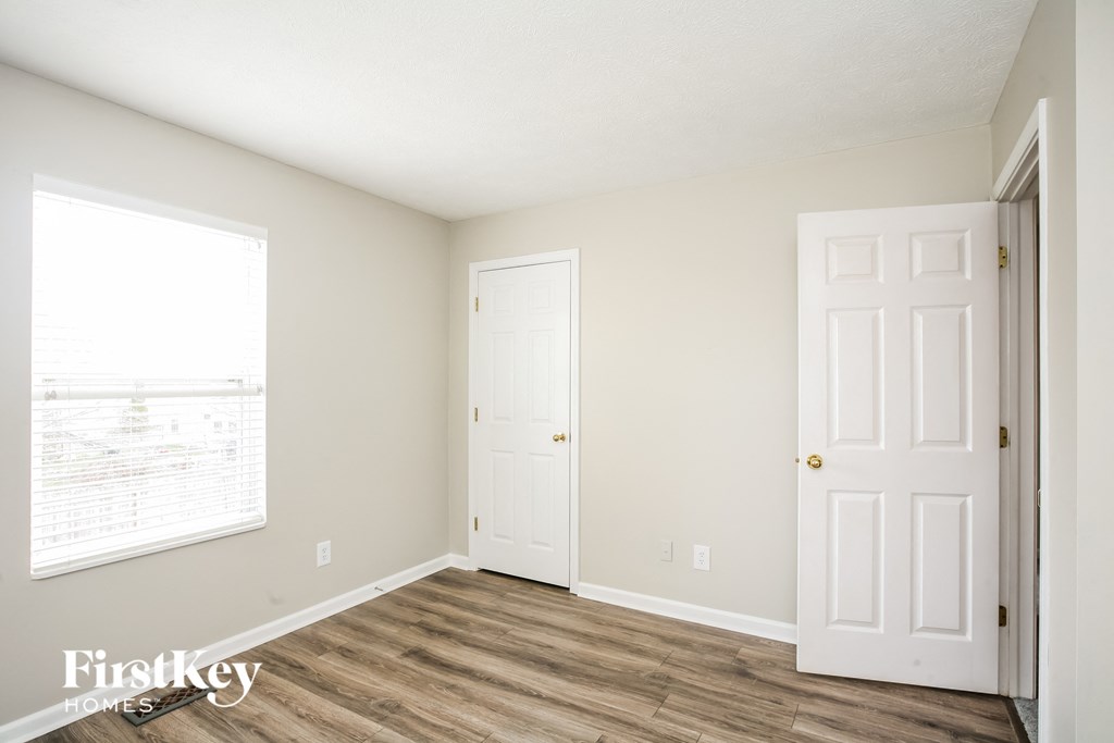 a bedroom with two doors and a window and a wood floor