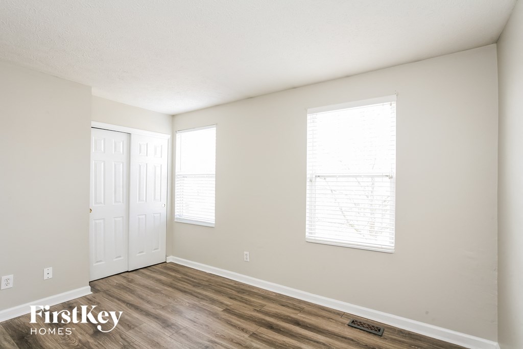the living room of an apartment with wood flooring and white walls