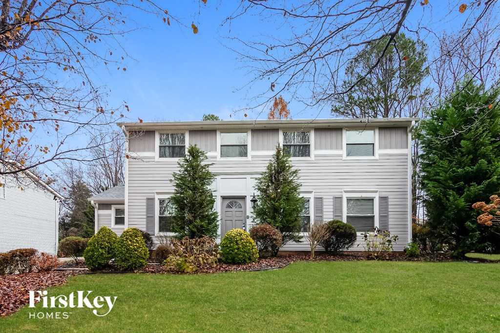 a white house with a lawn and trees in front of it