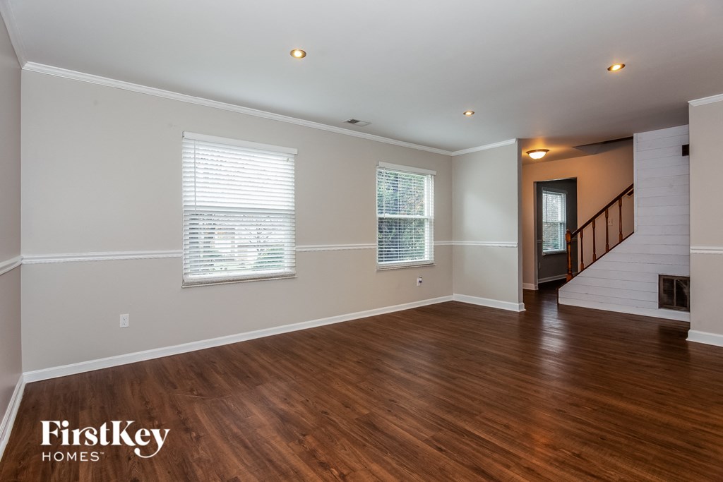 a living room with wood floors and white walls and a staircase