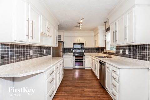 a large kitchen with white cabinets and white marble counter tops